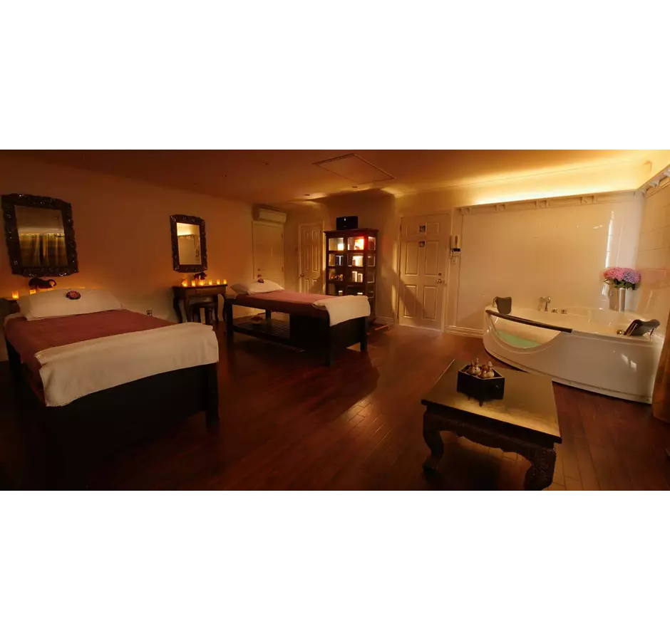 Room at Lotus Day Spa, dimly lit with candles, spa beds and spa bath.