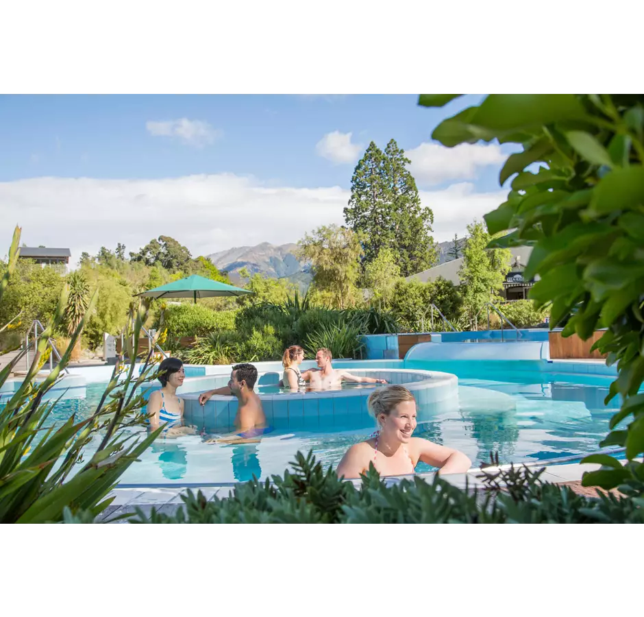 Guests enjoy the hot pools, blue skies with mountains in the background