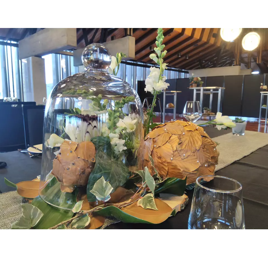 Table centerpiece, large green and brown leaves with flowers and glass dome over the top