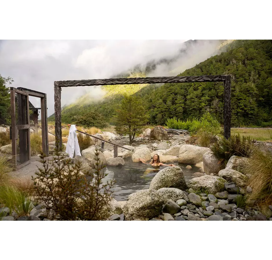 Lady enjoying Maruia Speings Hot Pools surrounded by native bush.